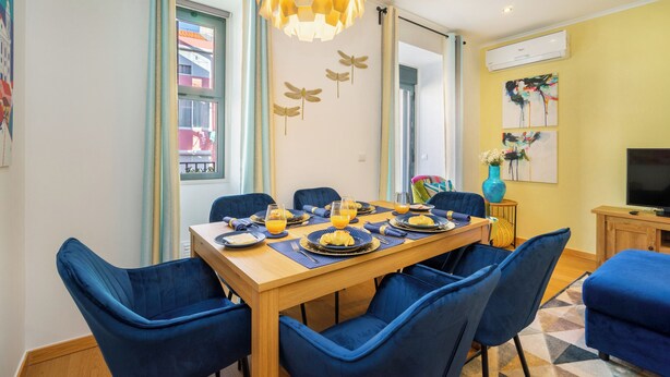 Een eethoek met een houten tafel, blauwe fauteuils en een hanglamp.