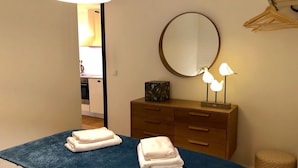 A hotel room with a bed, a dresser, a mirror, and a lamp.