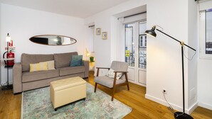 A living room with a sofa, ottoman, armchair, and a floor lamp.