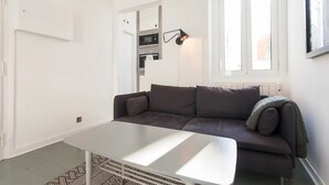 Ein modernes Wohnzimmer mit einem dunkelbraunen Sofa, einem weißen Couchtisch und einer Wandlampe.