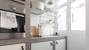 Eine moderne Küche mit Edelstahlgeräten, einem Fenster mit Blick und einem hängenden Küchenutensilienhalter.