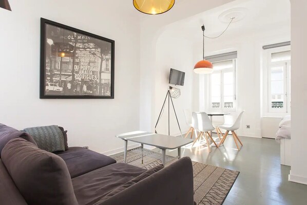 Een moderne woonkamer met een donkere bank, een salontafel en een zwart-wit foto in een lijst aan de muur.