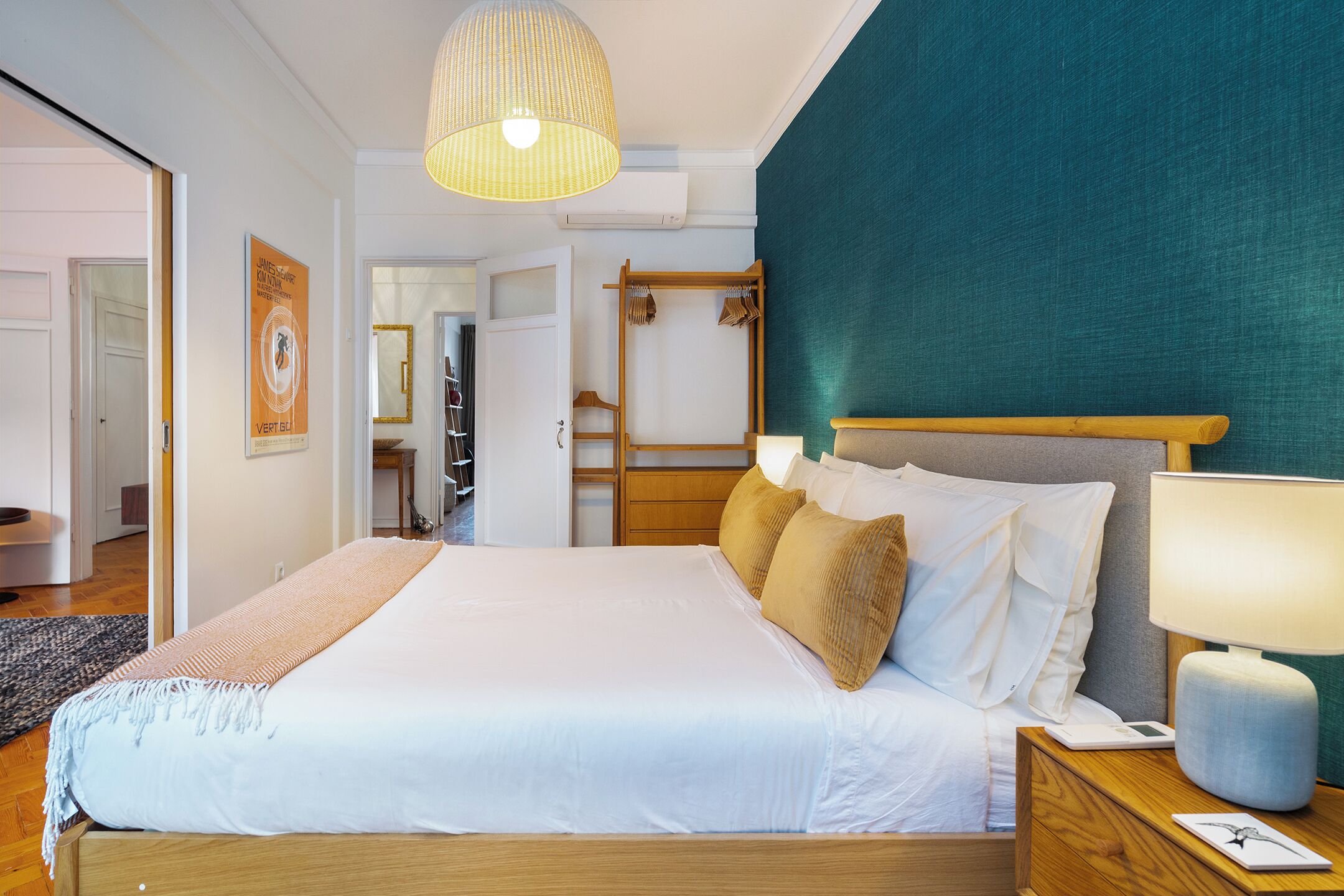 Cama bem arrumada com edredom branco e cabeceira de madeira.
