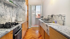 A compact kitchen with a gas stove, oven, and marble countertops.