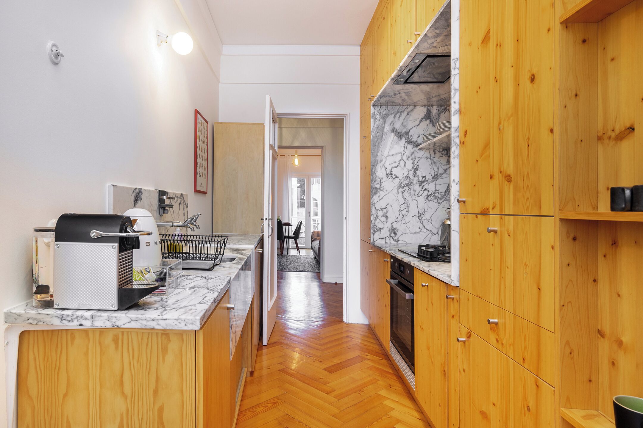 Eine moderne Küche mit Holzschränken, einer Marmorarbeitsplatte und einem eingebauten Ofen.
