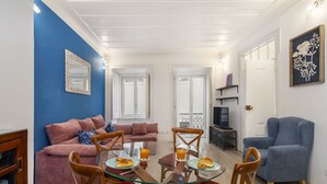 Una sala de estar con una mesa de centro de vidrio, dos sillones, un sofá y una televisión.