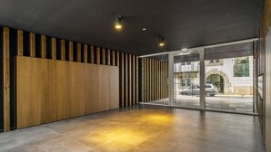 Un hall amplio con diseño moderno, que presenta un panel de madera y una entrada de vidrio hacia el exterior.