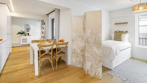 Una habitación moderna y bien iluminada con comedor, cama y un ventanal grande.