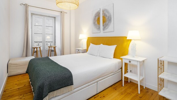 A bedroom with a bed, bedside tables, a window, and a hanging light fixture. - Dreamy Living Your Chic Graça Retreat (Lisbon)