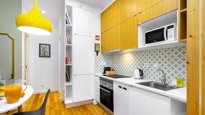 A modern kitchen with white cabinets, a microwave, a sink, and a wooden ceiling. - Dreamy Living Your Chic Graça Retreat (Lisbon)
