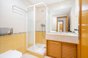 Ein modernes Badezimmer mit einer gläsernen Duschkabine, einem Holzwaschtisch und einem Händetrockner.