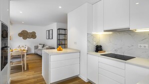 A modern kitchen with white cabinetry, a marble countertop, and a built-in stove.
