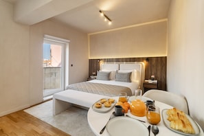 Relax in a spacious room with a large bed, bedside table, and breakfast table.
