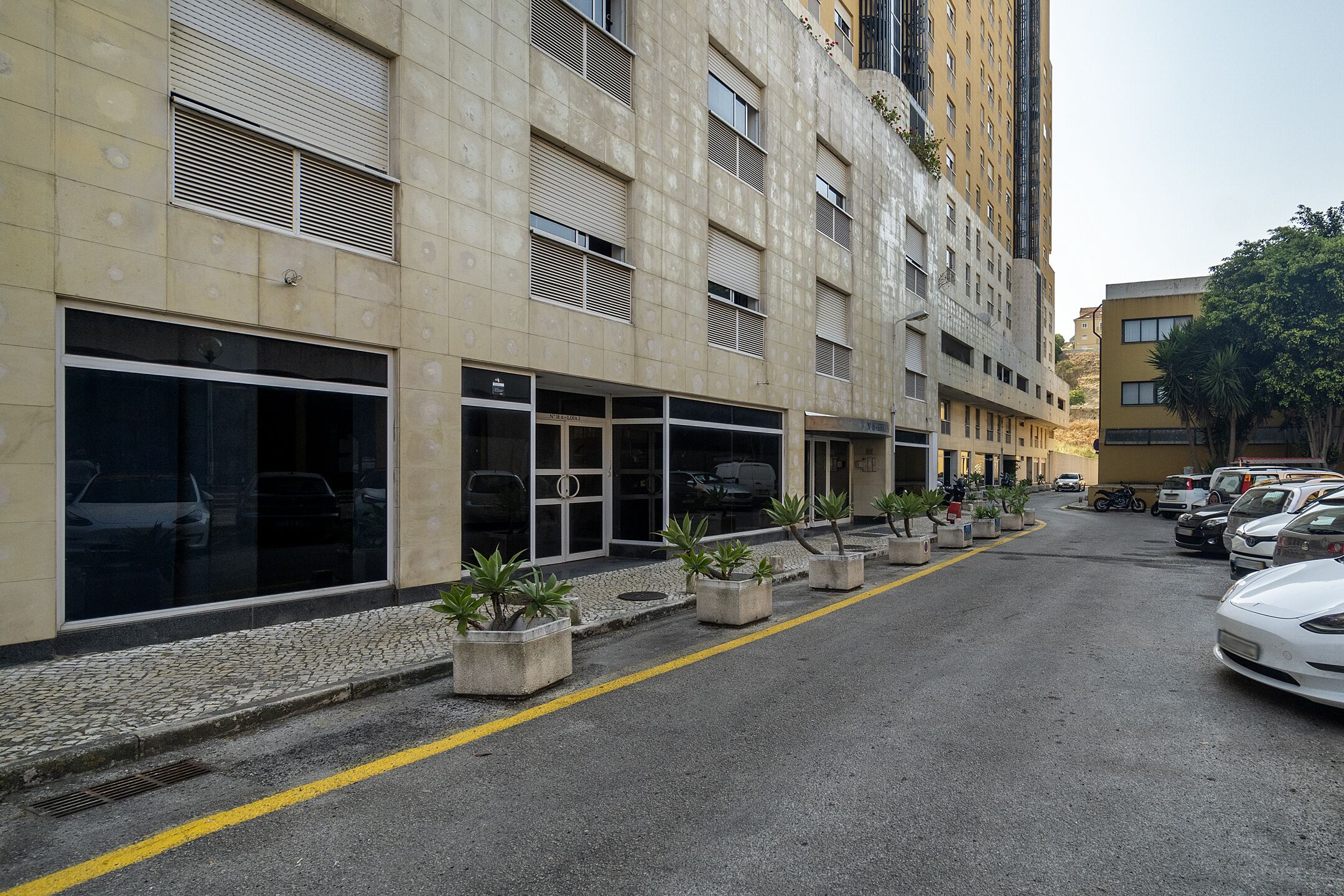 Un immeuble à plusieurs étages doté de grandes fenêtres et situé le long d’une rue pavée.