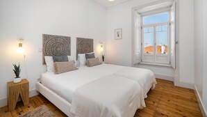 Une chambre avec deux lits, une grande fenêtre et un plancher en bois.
