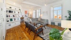 Un salon moderne avec un canapé d’angle, un plancher en bois et une bibliothèque.