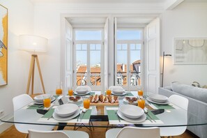 A dining area with a glass table, white chairs, and a breakfast spread including croissants and orange juice. - Classic Beauty & Modern Retreat In Príncipe Real (Lisbon)