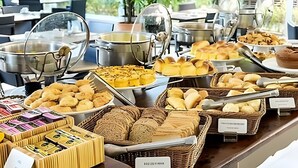 Un bufé con diversas opciones de comida, incluyendo panes, pasteles y una selección de quesos.
