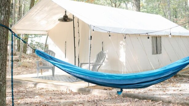 Een tent met een hangmat, een stoel en een klein terras.