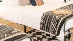 A tented room with a bed, pillows, a book, and a patterned blanket. - Site #36 Double Safari (Huntsville)