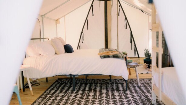 Ein Zeltraum mit einem Bett, einem gemusterten Teppich und einer Hängeleuchte.