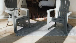 Una tenda con un letto, due sedie e una lampada a sospensione.