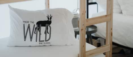 Ein Stockbett mit weißer Matratze und Kopfkissen mit einem Motiv eines Wildtiers.