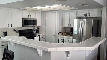 Una cocina con armarios blancos, un refrigerador de acero inoxidable y un microondas.