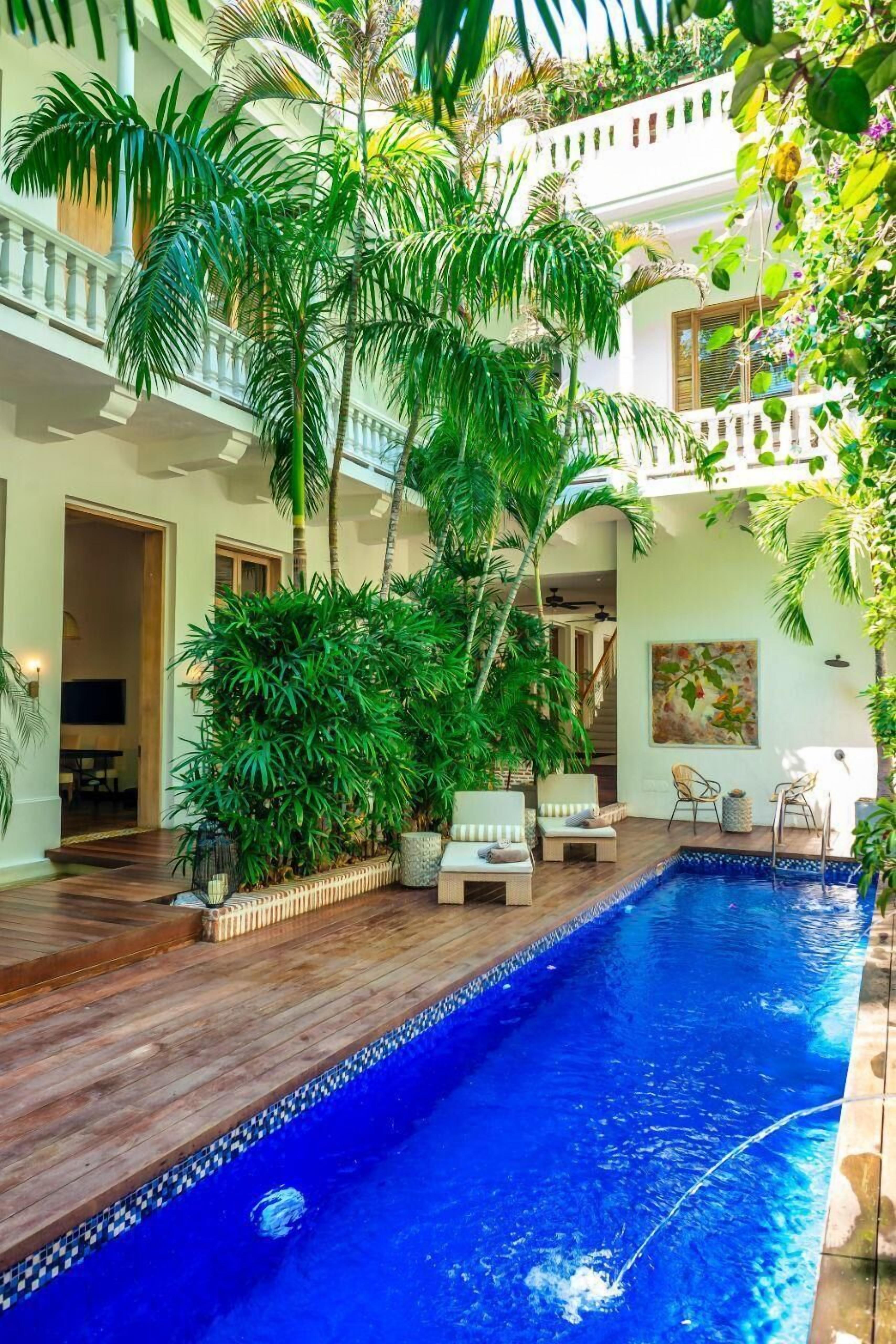 Una piscina al aire libre, sombrillas, sillones reclinables de piscina