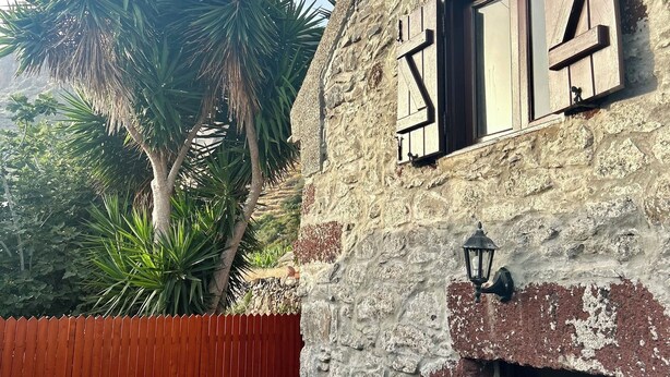 A rustic stone building with a wooden door marked "B2" and a wooden window with a cross-shaped shutter. - Palheiro Jardim by Olá Madeira (Paúl do Mar)