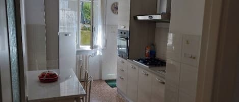 A kitchen with white cabinets, a stove, and a dining area with a table and chairs.