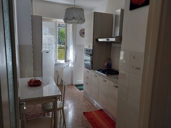 A kitchen with white cabinets, a stove, and a dining area with a table and chairs.