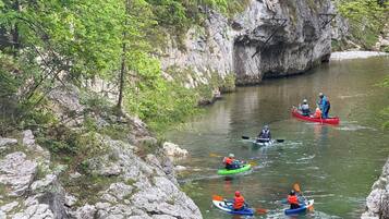 A group of kayakers on a river surrounded by rocky cliffs and greenery.