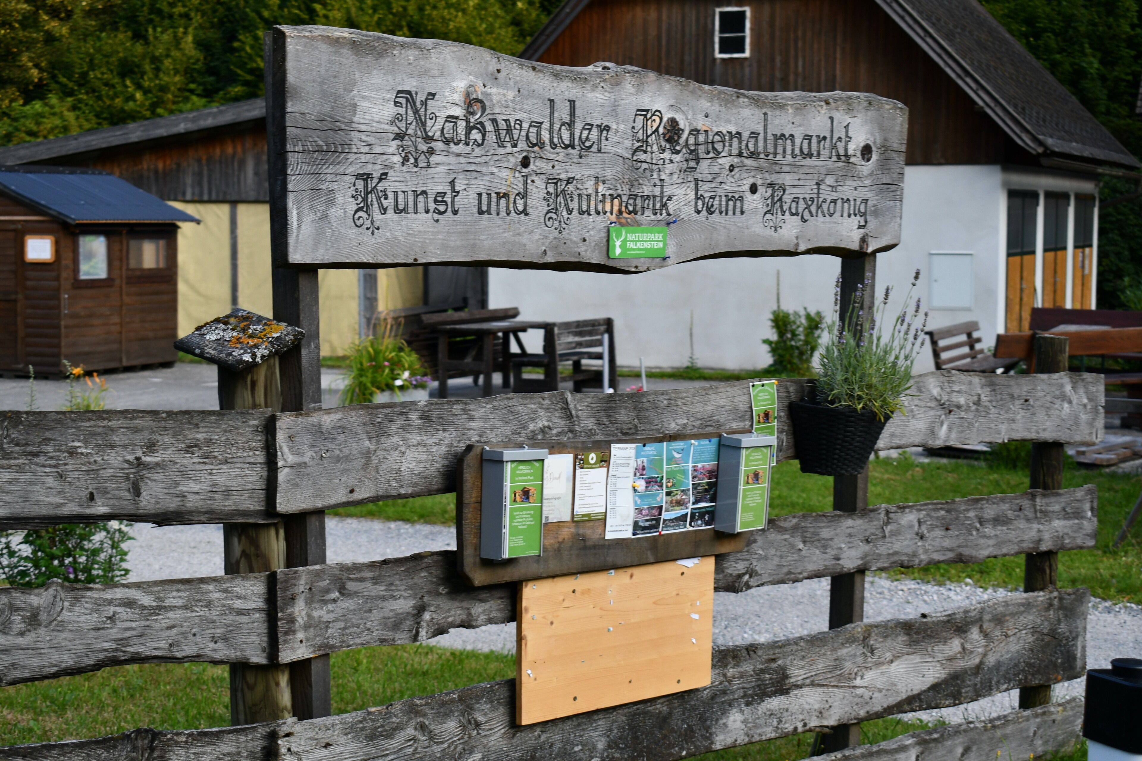 A wooden sign with text and a bulletin board with papers.
