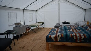 Ein Zelt mit Bett, Stuhl, kleinem Tisch und Bank.