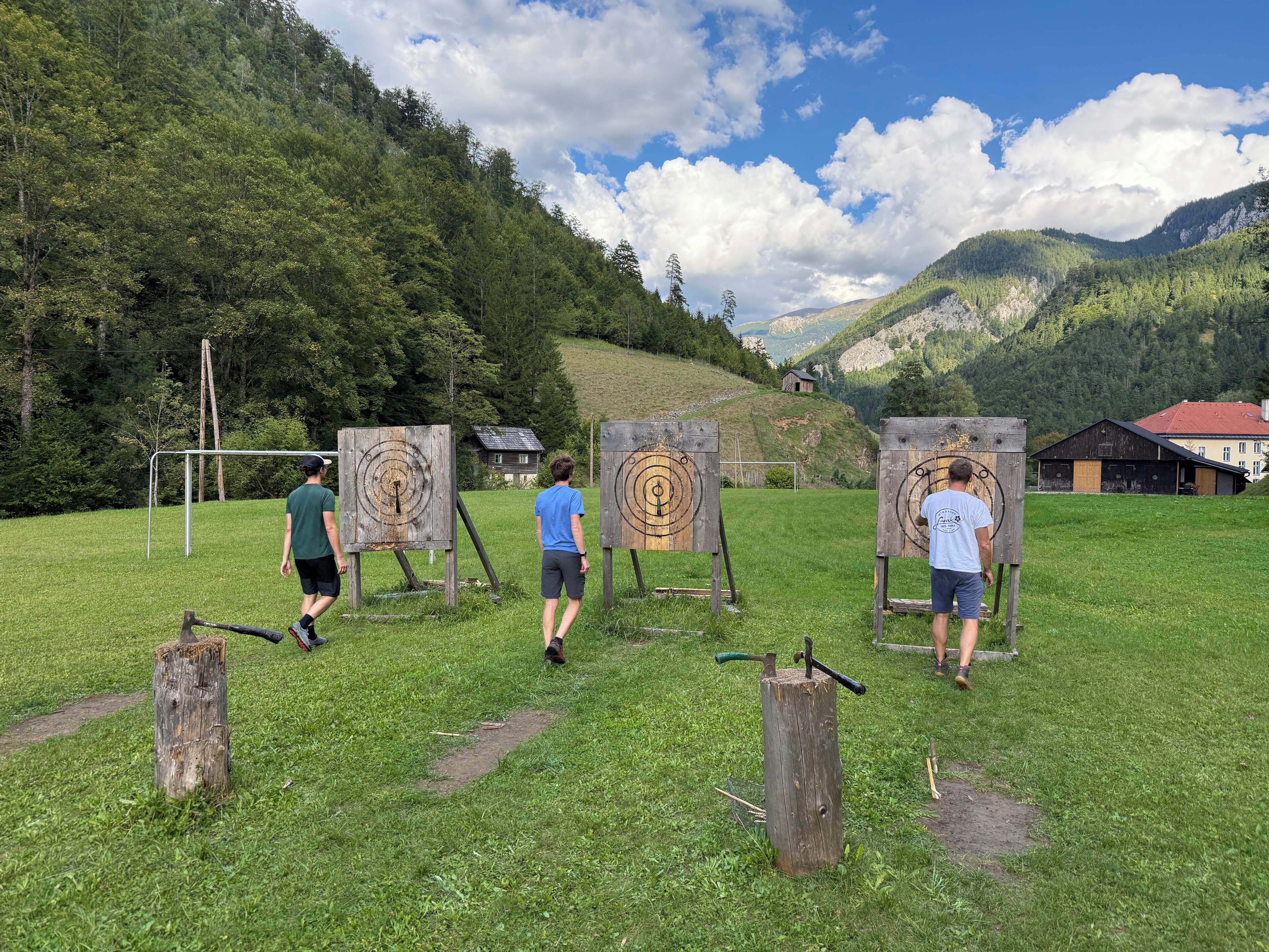 A grassy field with wooden archery targets and a goalpost.