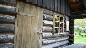 Eine rustikale Holzhütte mit Holztür und -fenster, einer Bank davor und einem Schild, das ein Restaurant anzeigt.
