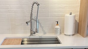 Una cocina moderna con un lavamanos de acero inoxidable, armarios de madera y un lavavajillas empotrado.