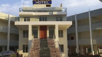 A hotel with a central staircase leading to the entrance, multiple floors, and a sign above the entrance.