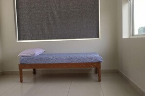 A small, simple room with a wooden bench, a large window, and a plain wall.