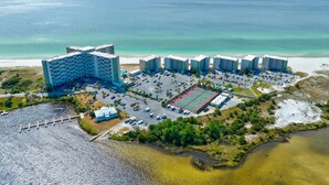 Vista aérea de um hotel à beira-mar, com vários edifícios, estacionamento e praia.