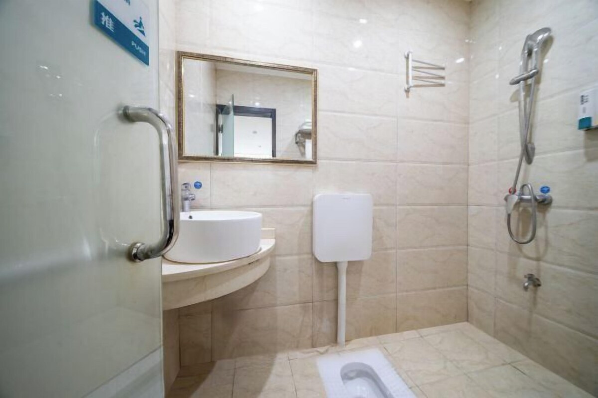 A bathroom with a sink, mirror, toilet, and shower.