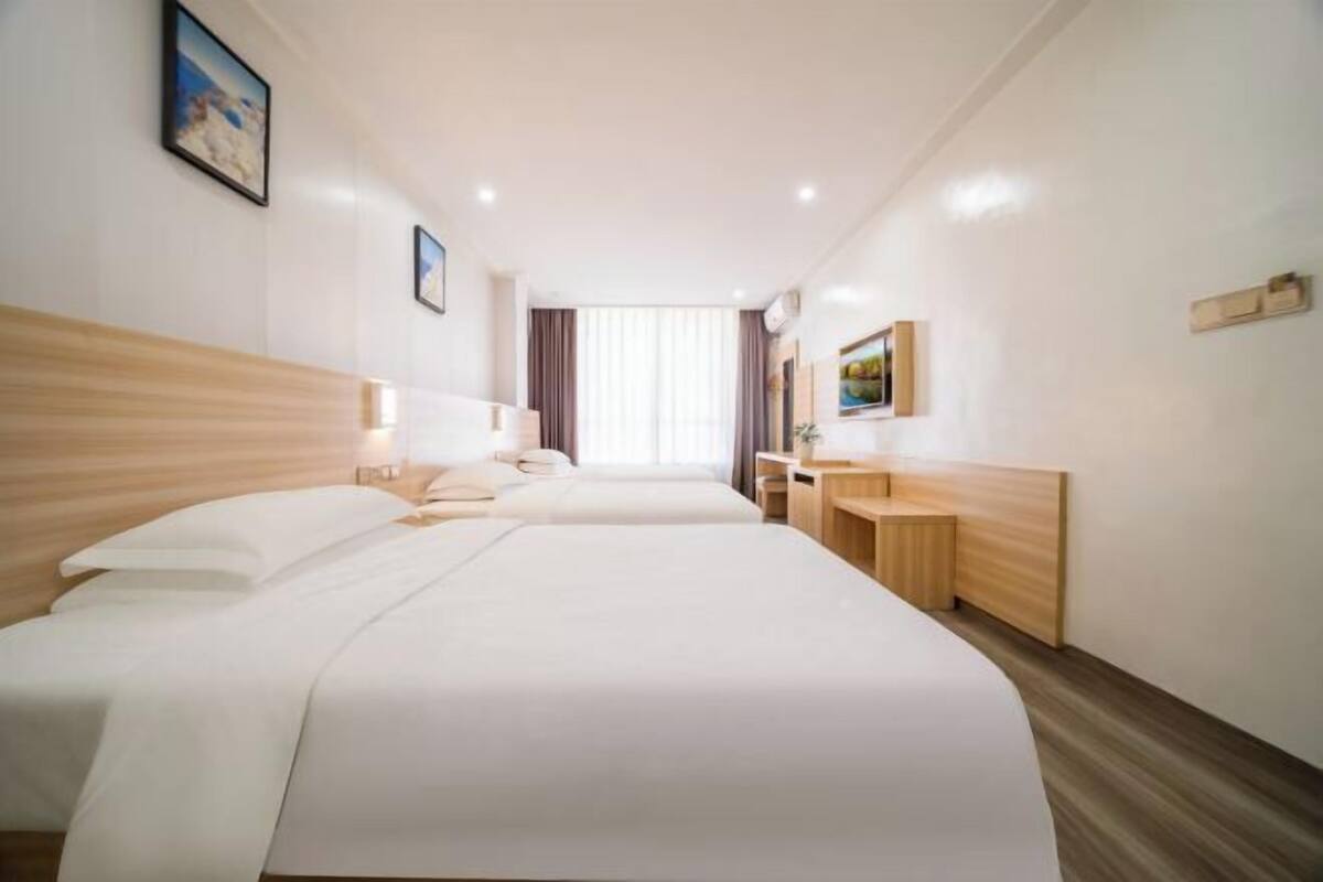Habitación de hotel con dos camas, cabecero de madera, escritorio y ventana con cortinas.