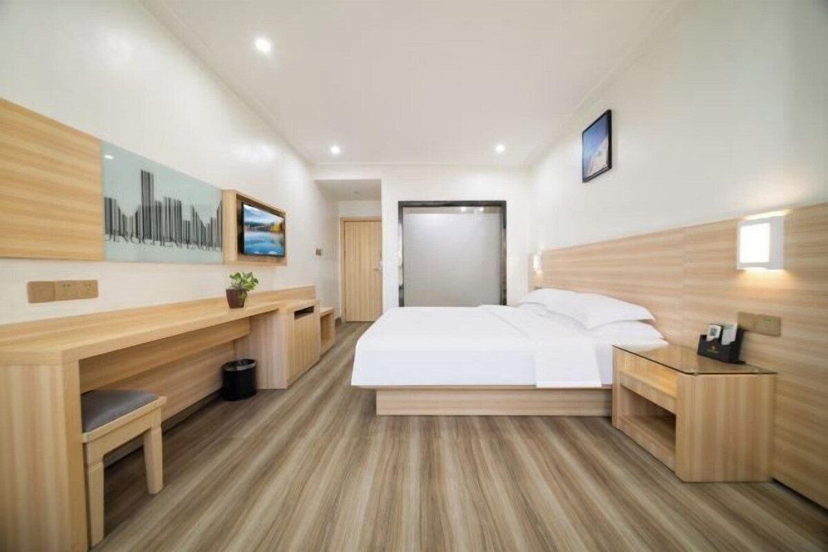 Ein modernes Hotelzimmer mit einem großen Bett, Holzmöbeln, einem Schreibtisch und einem Bild an der Wand.
