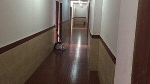 Um corredor comprido e estreito, com soalho de madeira e paredes brancas.