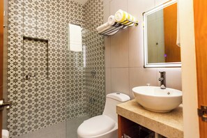 A bathroom with a patterned tile wall, a toilet, a sink, and a towel rack with towels.