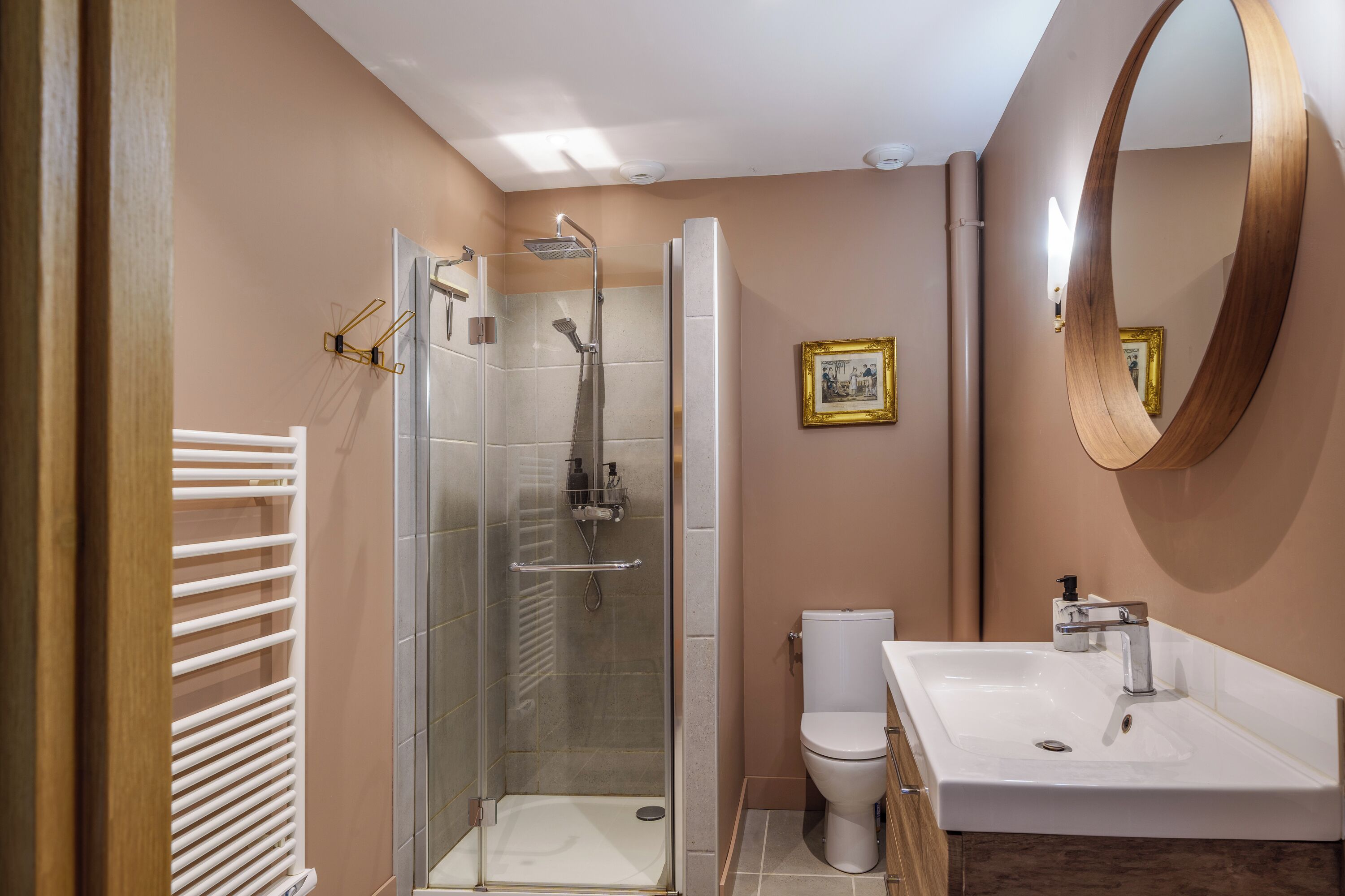 Un baño moderno con ducha de vidrio, lavamanos blanco y un espejo grande.