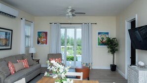 Un salon avec un canapé, une table basse, un téléviseur et un ventilateur de plafond.