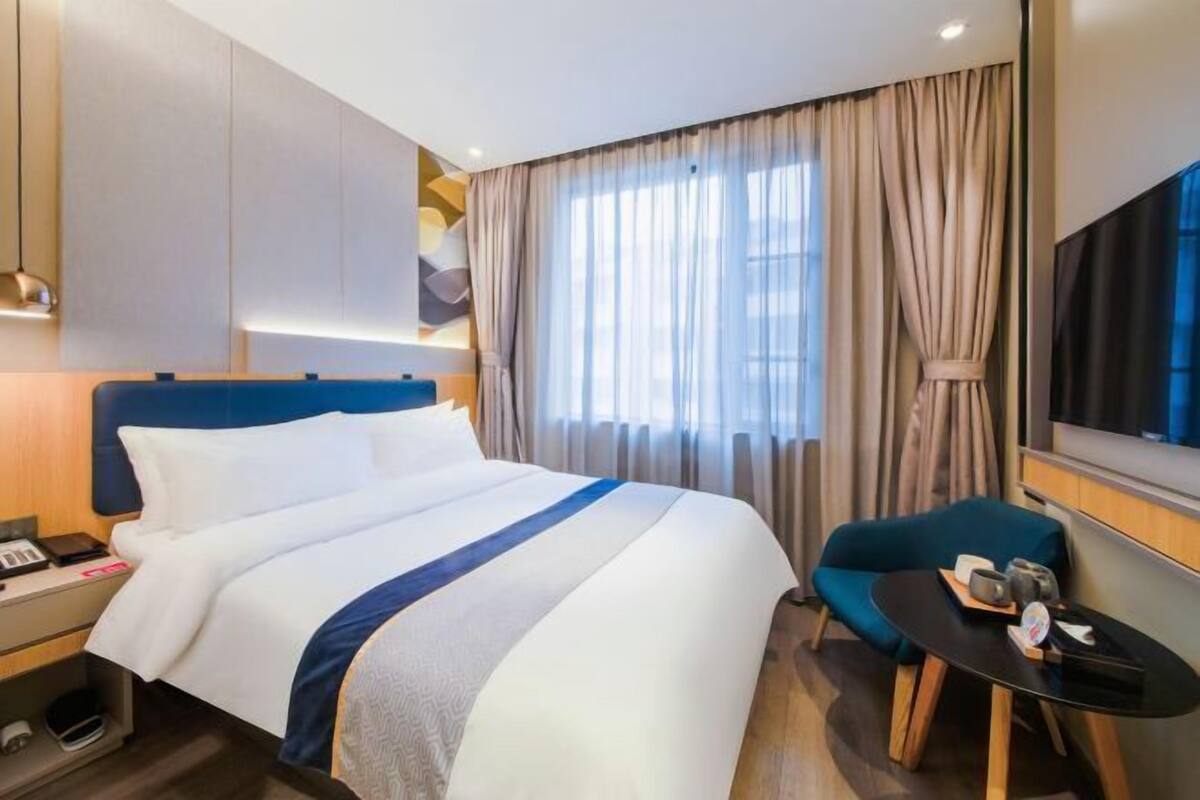 Een hotelkamer met een bed, een bureau, een stoel en een televisie.