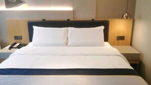 A hotel room with a bed, bedside tables, a phone, and a wall-mounted light fixture. - Homeinn Selected Hotel (Shanghai Convention Center Qibao Metro Station) (Shanghai)